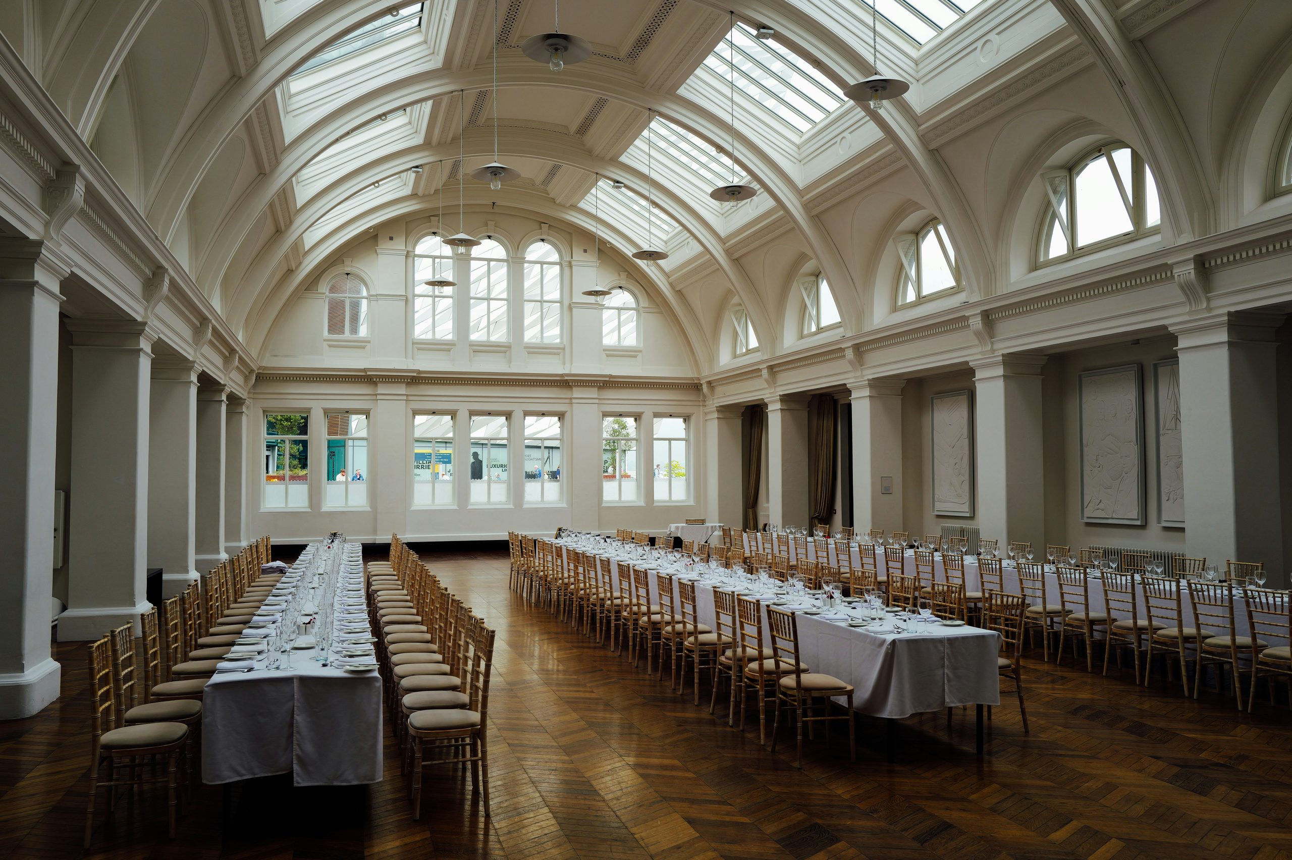 Long banquet tables set in a grand hall before guests arrive