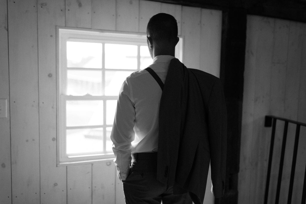 Event operations lead in a white shirt and suspenders preparing for an event by a window